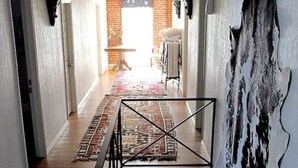 Un couloir doté d’un plancher en bois, d’une rambarde en métal noir et d’un tapis à motifs.