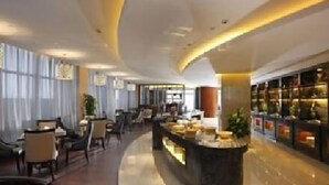 A modern hotel lobby with a curved reception desk, seating area, and a display of items on the right. - Shuguang International Hotel Huaian (Huai'an)