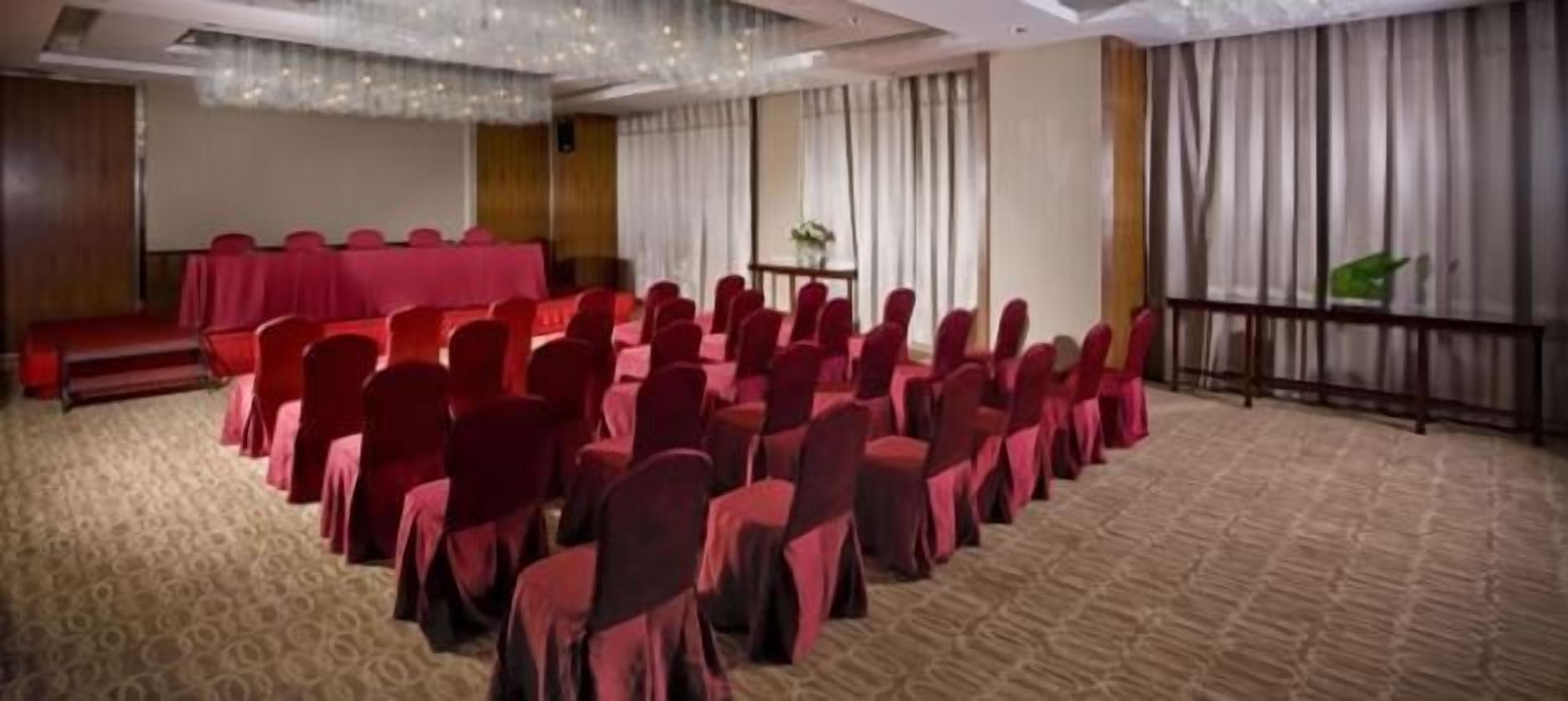 A conference room with rows of chairs, a stage, and a carpeted floor.