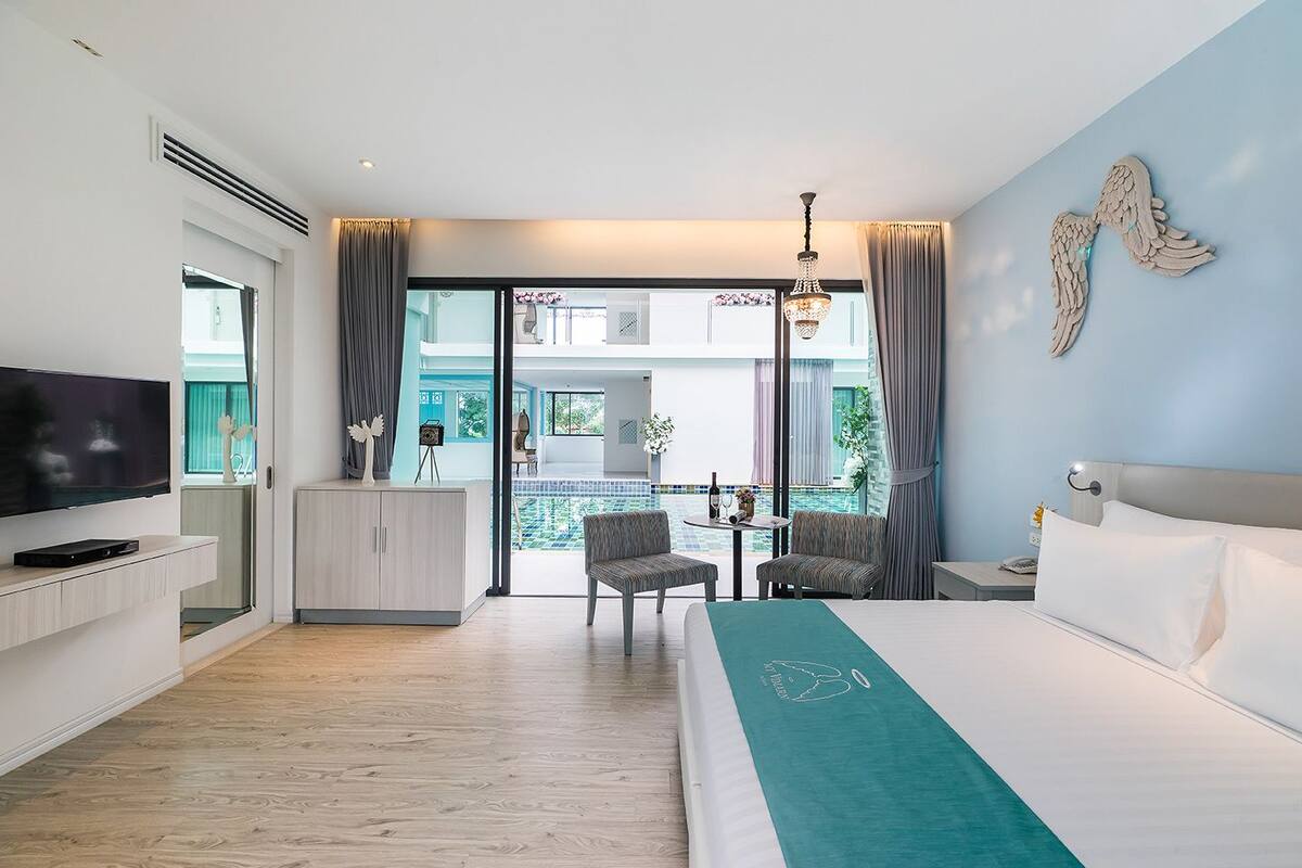Et hotelværelse med seng, tv, skrivebord og udsigt til pool og udendørs område.