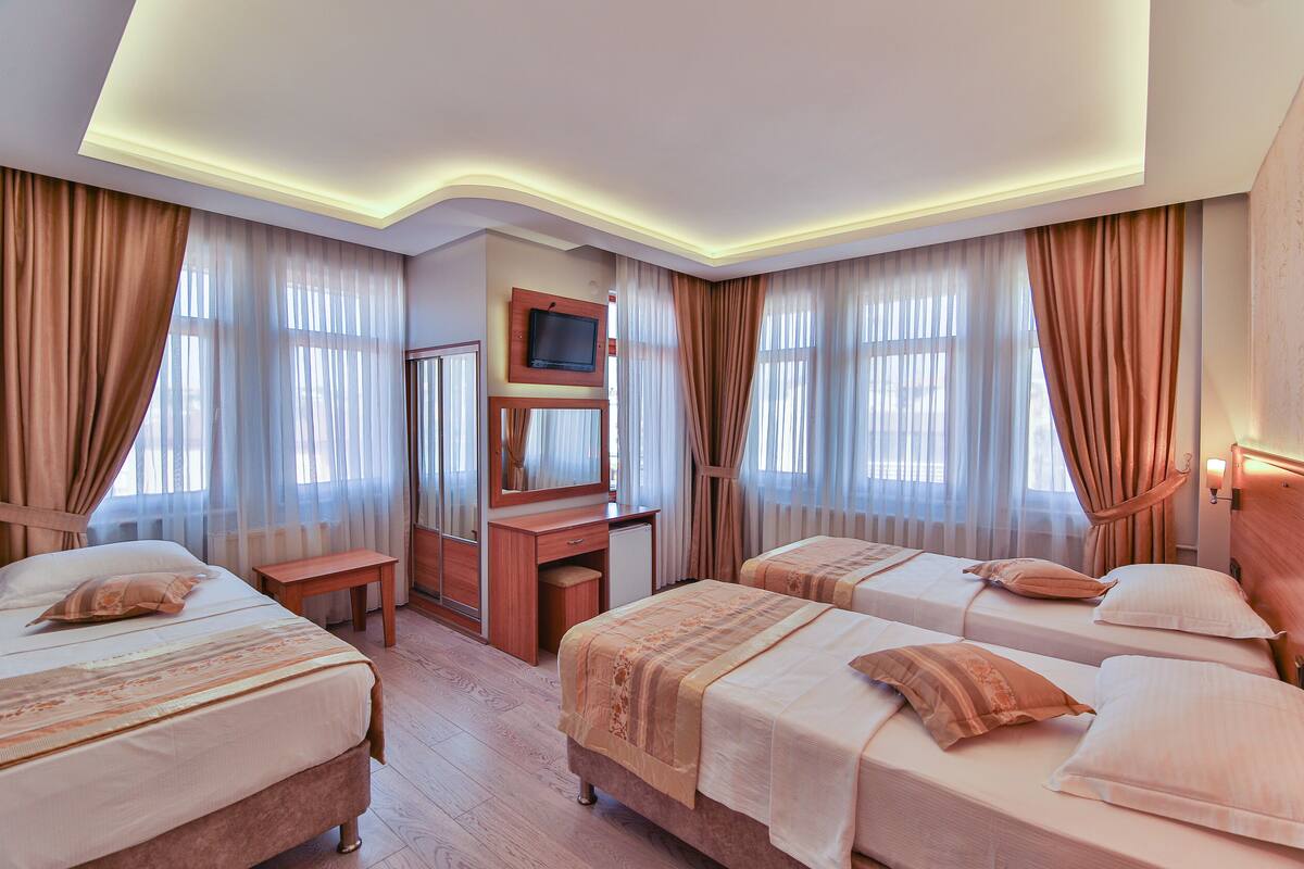 A hotel room with two beds, a desk, a television, and a mirror.