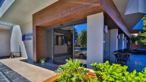 A modern hotel exterior with a glass entrance, outdoor seating, and a well-maintained garden area. - Seymen Hotel (Amasra)
