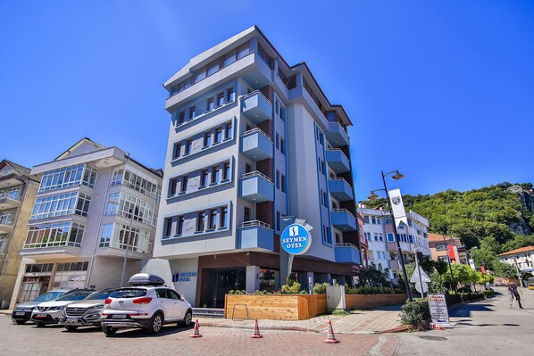 A multi-story hotel with a prominent sign, balconies, and a parking area. - Seymen Hotel (Amasra)