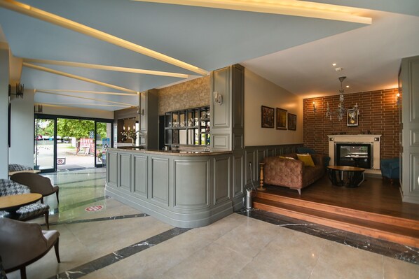 A lobby with a bar area, seating, a fireplace, and a view of the outdoors.