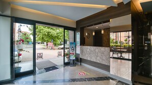 A hotel lobby with a reception desk, a glass door entrance, a parking sign, and a small outdoor seating area visible through the glass. - Seymen Hotel (Amasra)