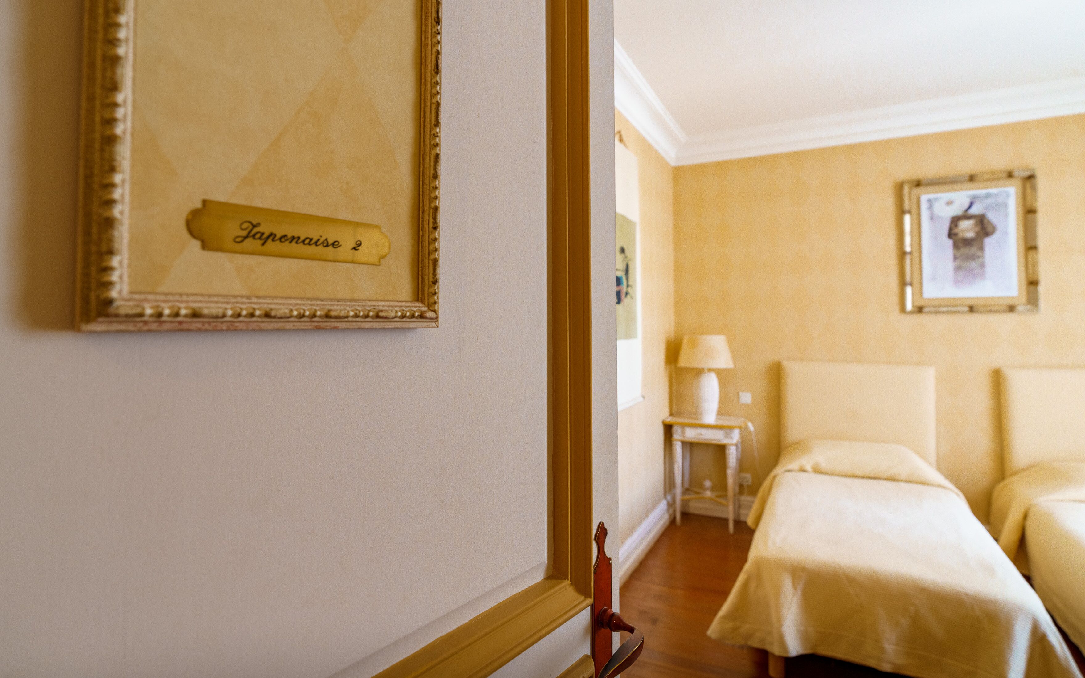 Una habitación de hotel con una cama, una mesita de noche, una lámpara y un cuadro en la pared.