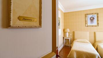 Una habitación de hotel con una cama, una mesita de noche, una lámpara y un cuadro en la pared.