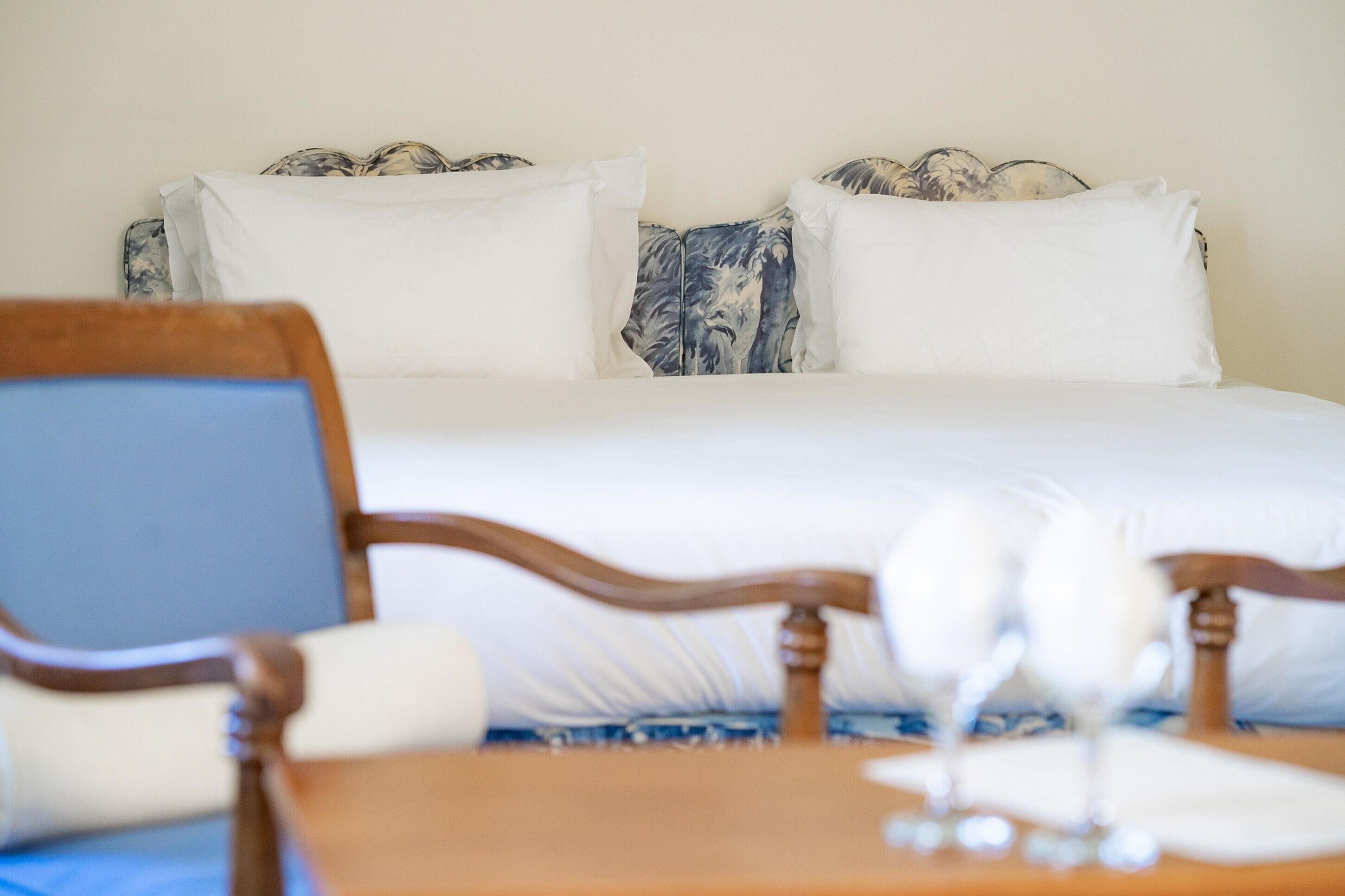 Un letto rifatto con lenzuola bianche e una testiera decorata con motivi floreali.