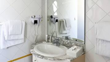A bathroom with a white sink, a mirror, and two hair dryers mounted on the wall.