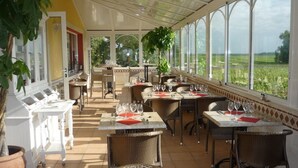 Een restaurant met terras, grote ramen en uitzicht op het landschap.