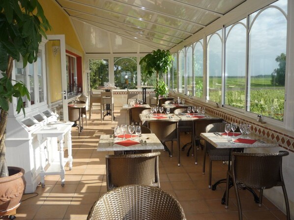 Een restaurant met terras, grote ramen en uitzicht op het landschap.
