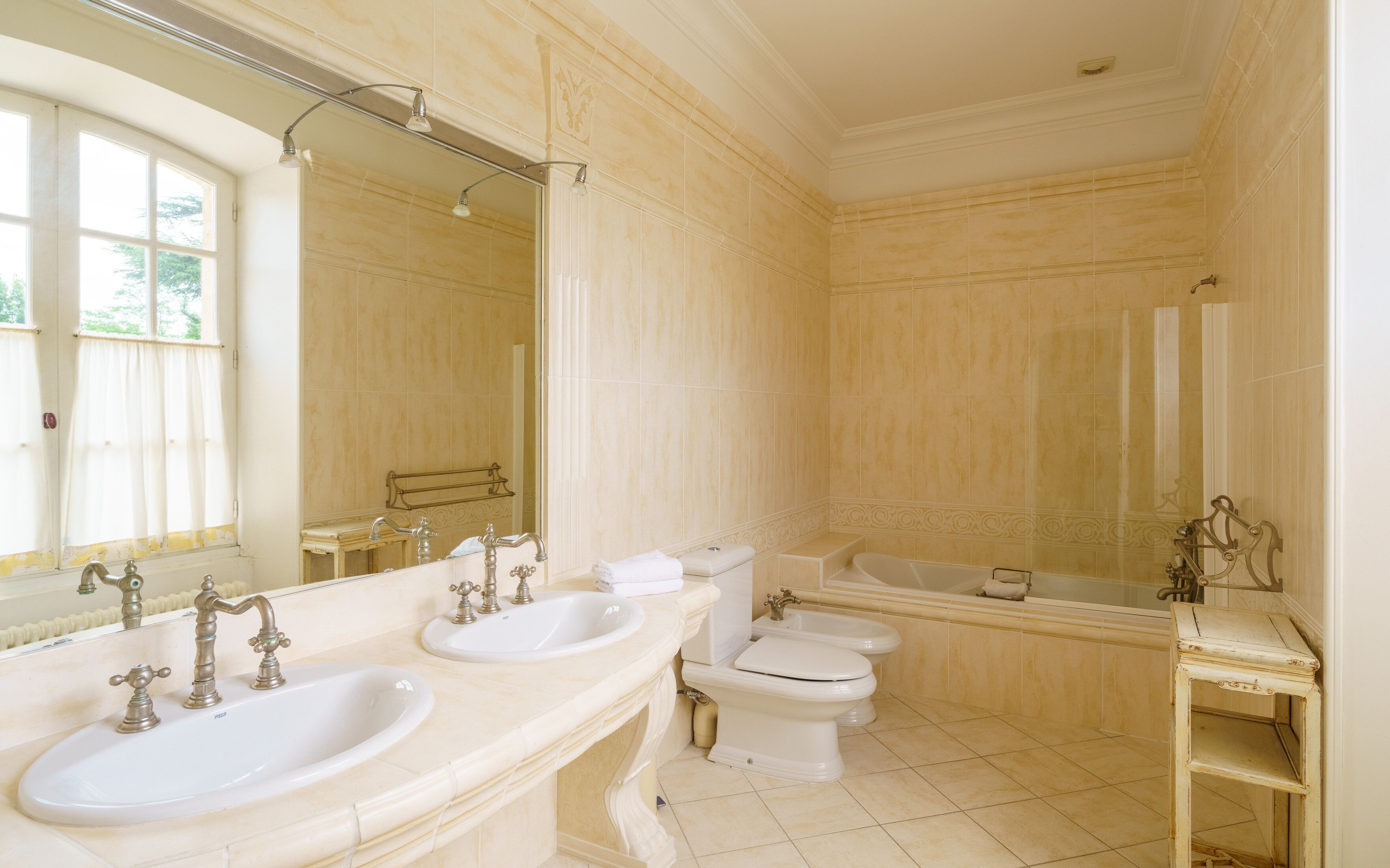 A bathroom with two sinks, a toilet, a bathtub, and a large mirror.