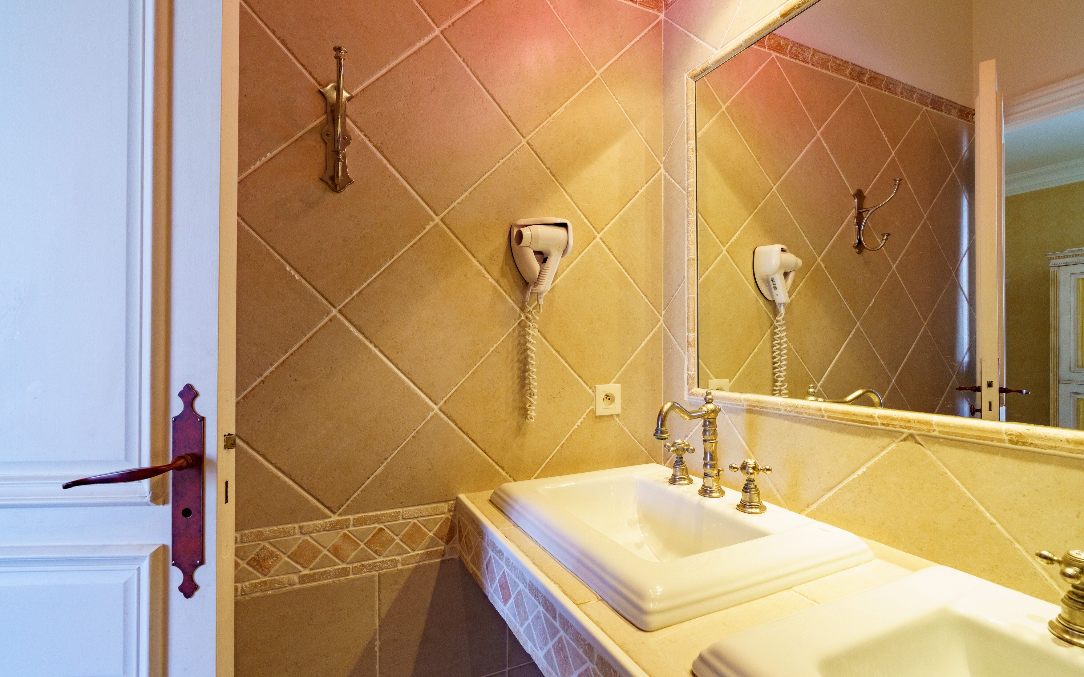 Baño con dos lavamanos, un espejo y un secador de pelo fijado en la pared.