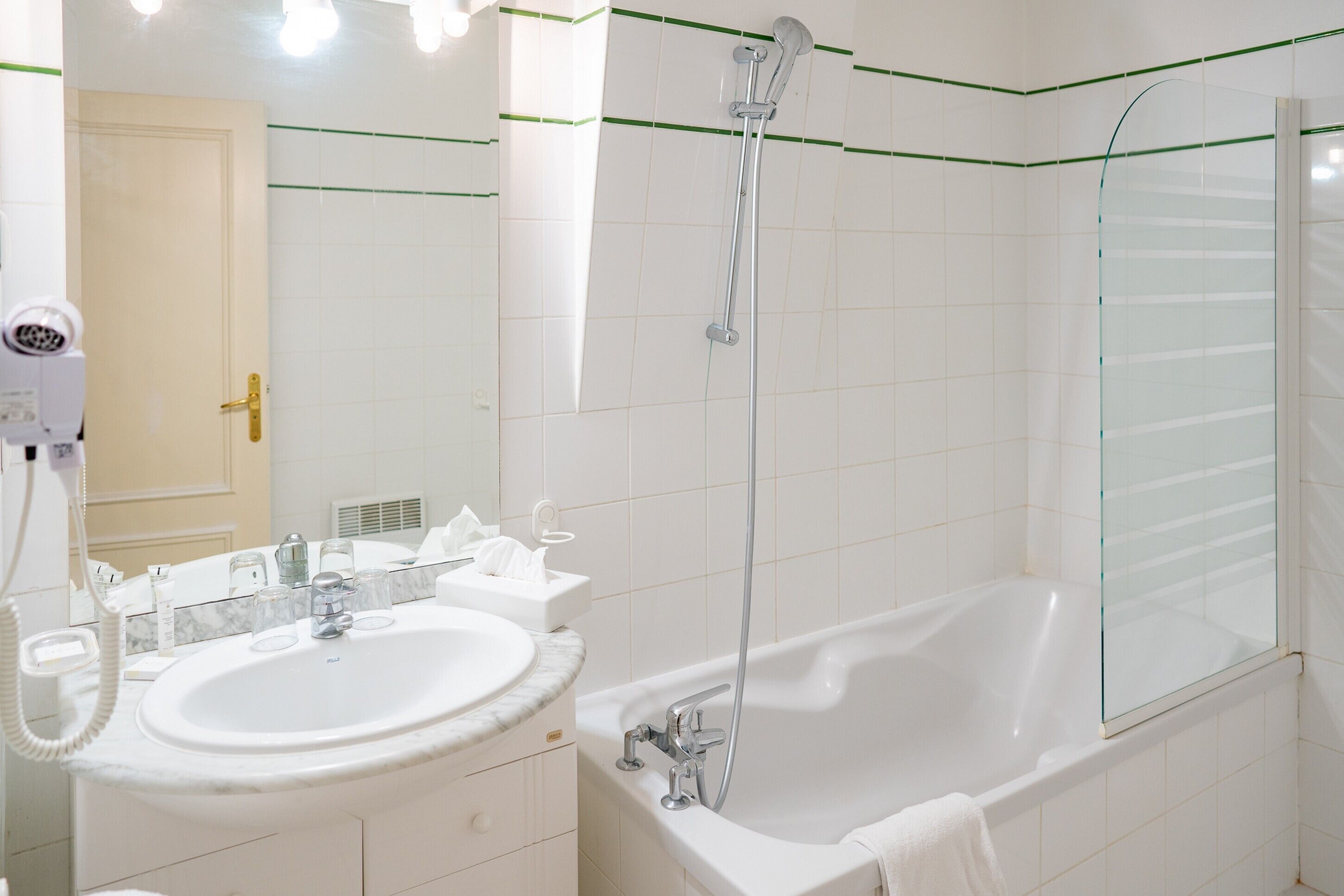 Un baño moderno con lavamanos, espejo y bañera blancos.