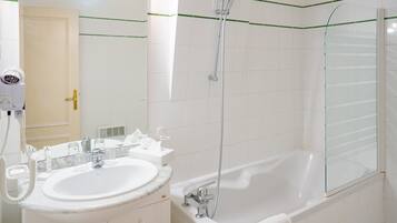 Un baño moderno con lavamanos, espejo y bañera blancos.