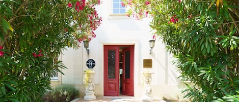 Entrada de hotel con puerta roja, señal que indica que es un hotel y estatua de niño.