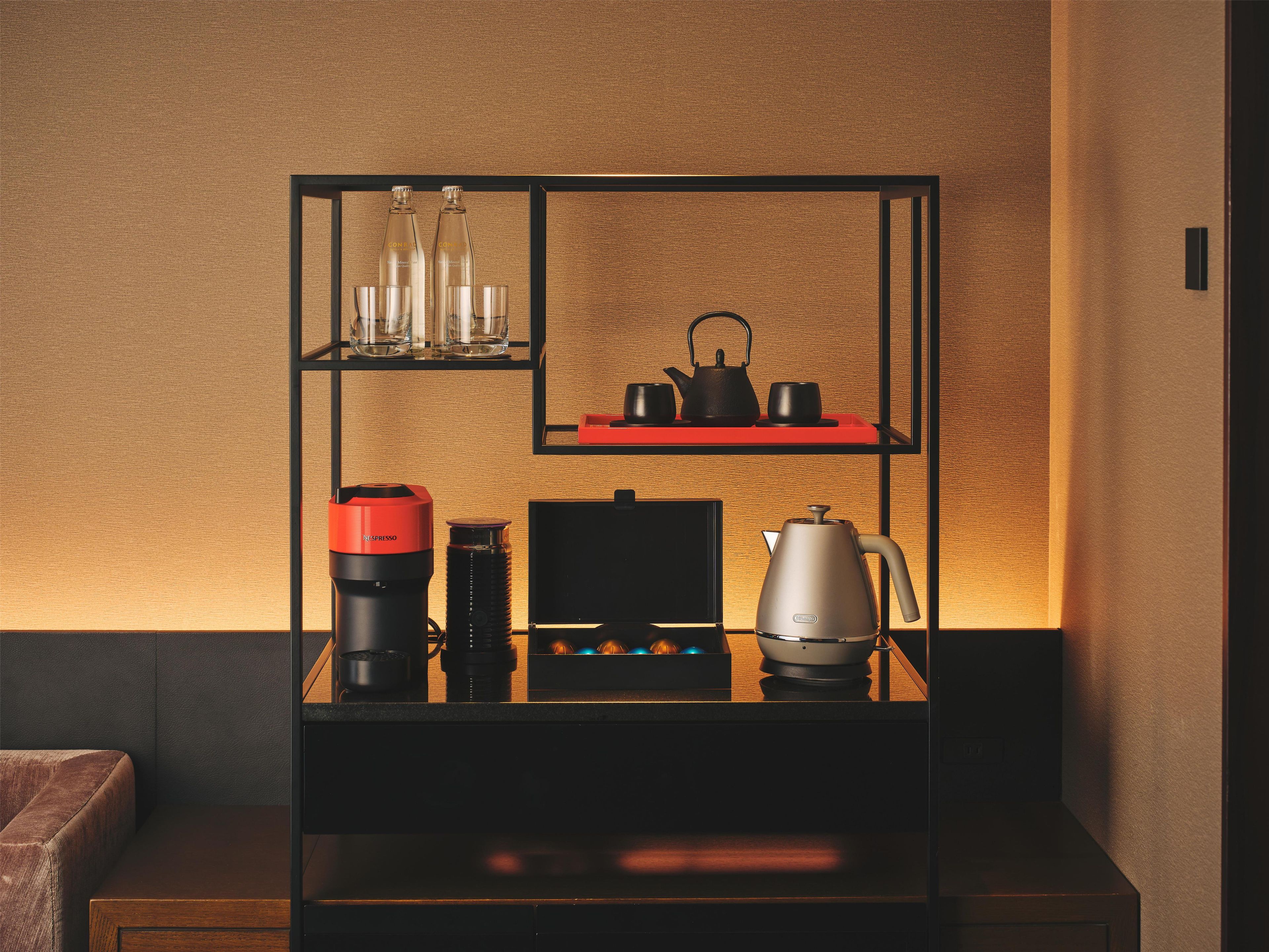 Una cocina moderna con cafetera, hervidor y juego de té sobre una encimera negra.