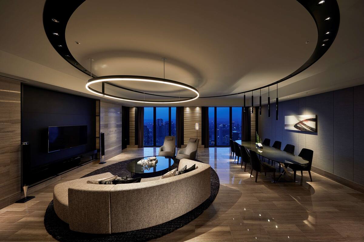 A modern living room with a circular coffee table, a flat-screen TV, and a dining area with a table and chairs.