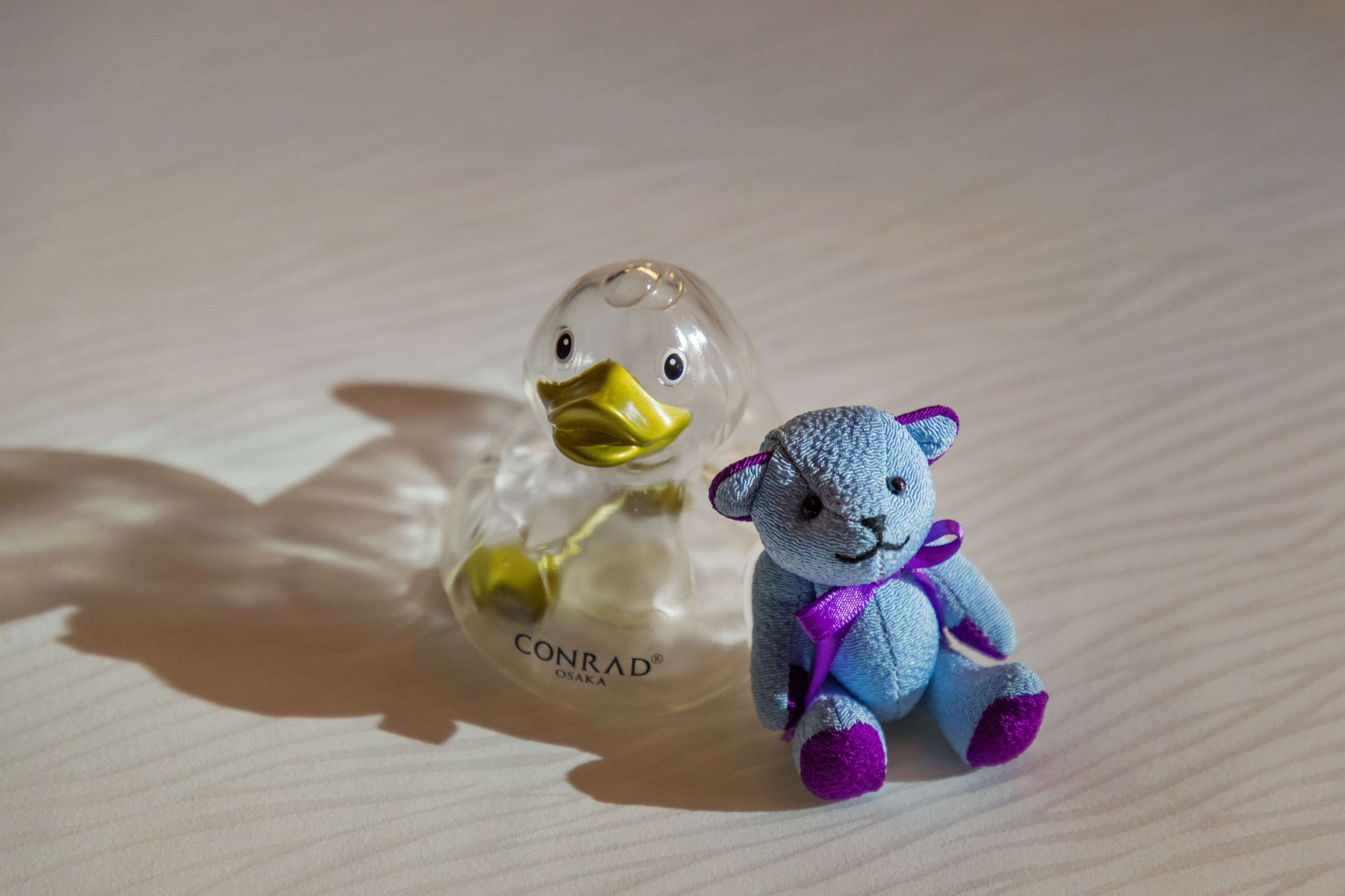Une petite figurine représentant un canard et un ours, posée sur une surface texturée.