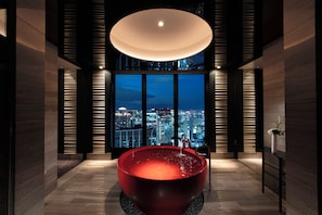 A modern bathroom with a large bathtub, a city view through floor-to-ceiling windows, and a unique lighting fixture. - Conrad Osaka (Osaka)