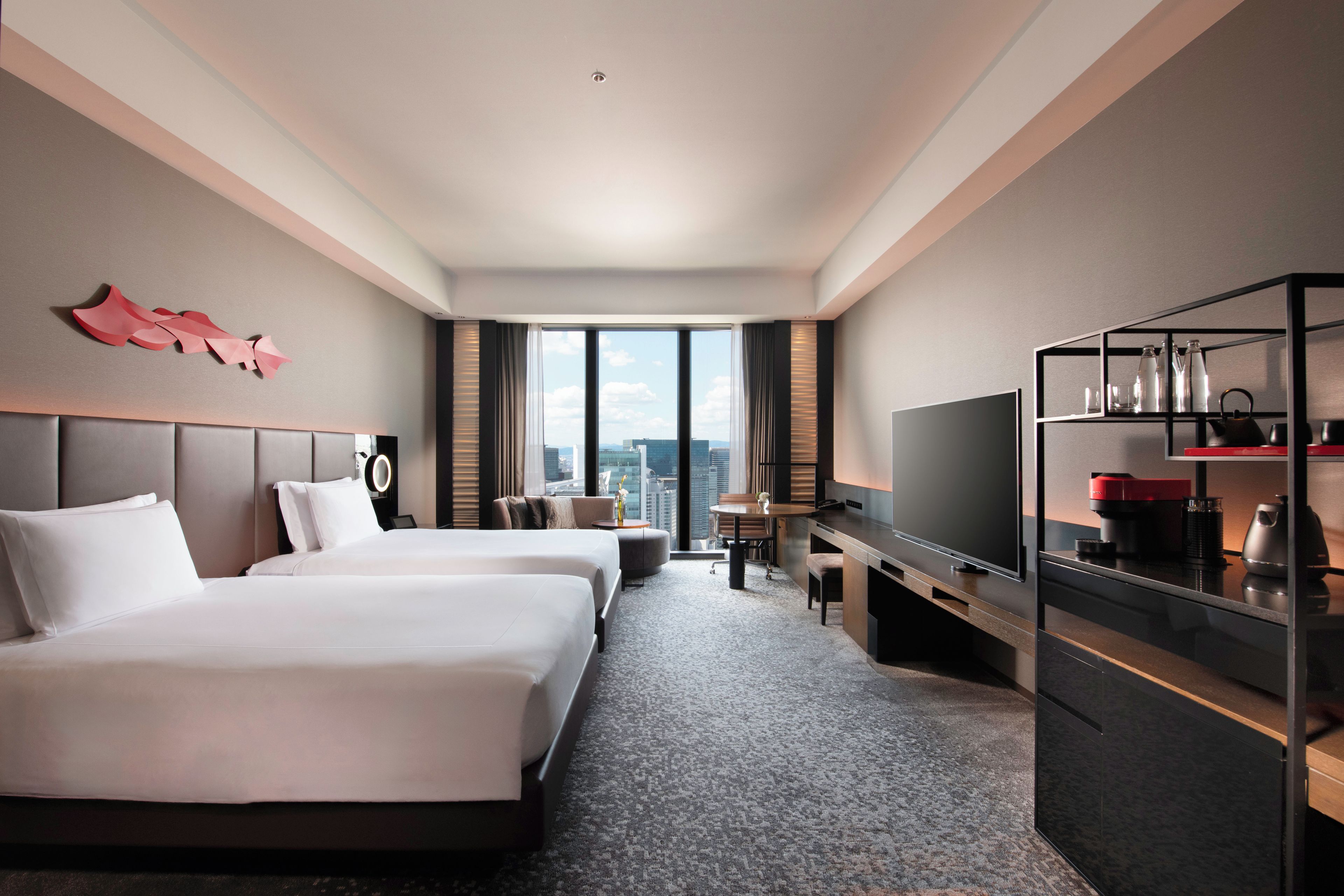 Quarto de hotel com duas camas, uma escrivaninha, televisão e minibar.