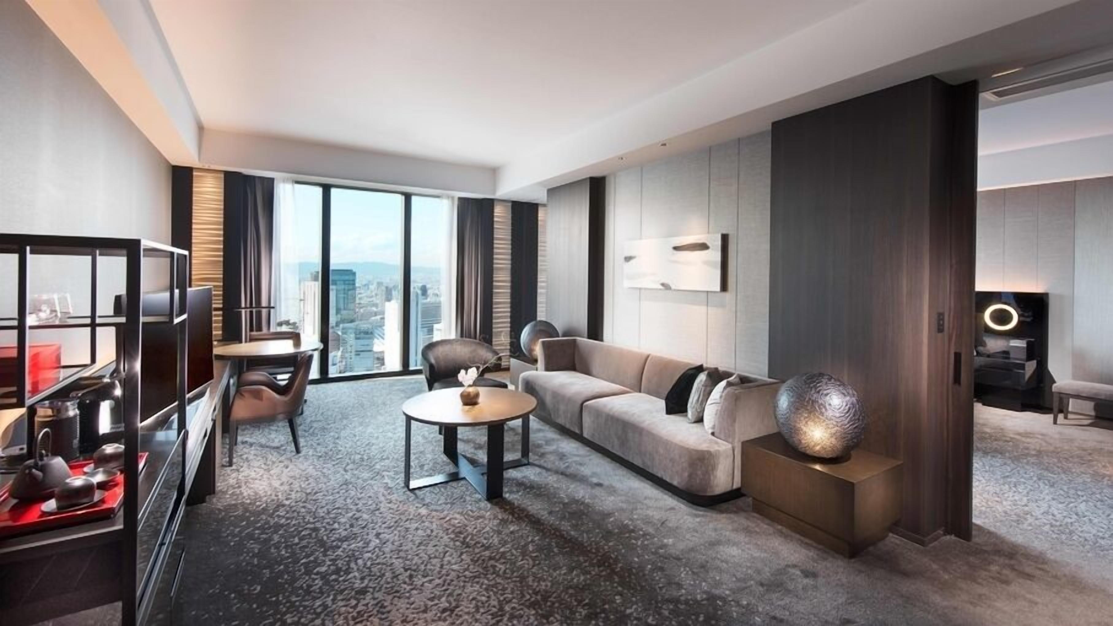 Une chambre d’hôtel moderne avec vue sur la ville, comprenant un canapé, un coin repas et un téléviseur.