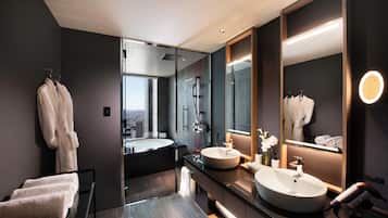 A modern bathroom with dual sinks, a large mirror, and a glass-enclosed shower.