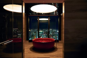 A modern interior with a red bathtub, large windows, and a city view. - Conrad Osaka (Osaka)