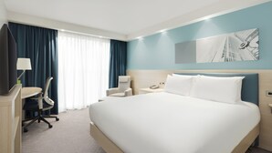 Una camera d'albergo con un letto grande, una scrivania con una sedia, un telefono e un quadro appeso al muro.