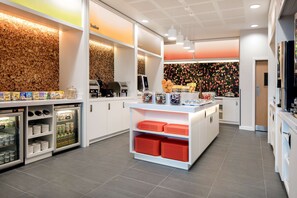 A modern kitchen with white cabinets, a central island, and a variety of appliances including a coffee machine and a refrigerator. - Hampton by Hilton London Excel (London)