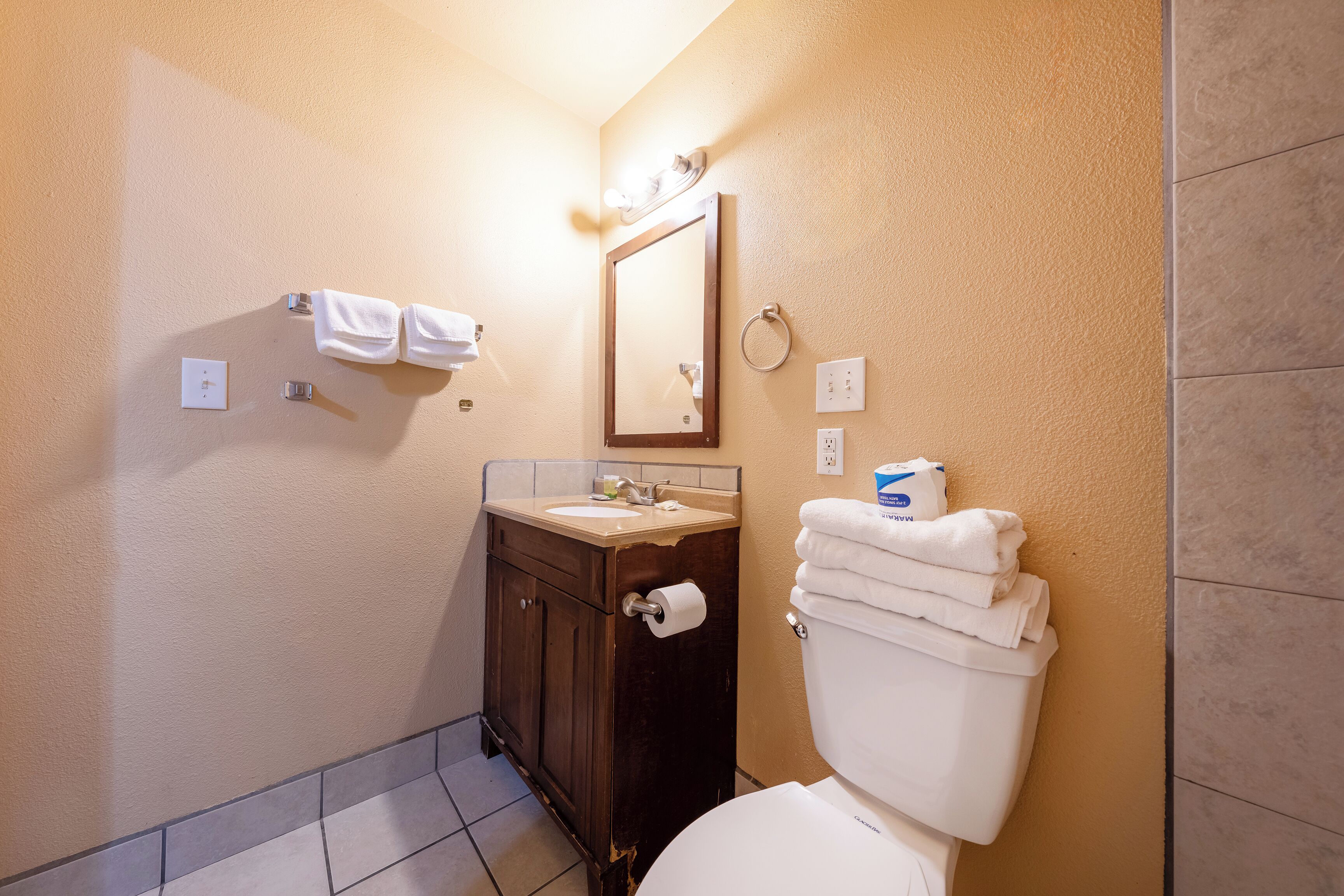 Een badkamer met toilet, wastafel en spiegel.