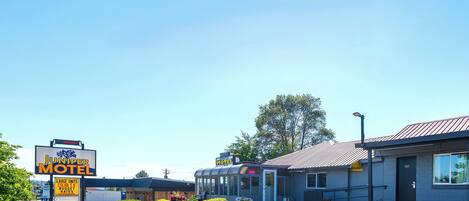 A Juniper Motel with a large sign, a parking lot, and a building with a metal roof.