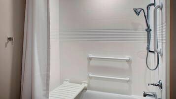 A bathroom with a shower, a white bathtub, and a grab bar.
