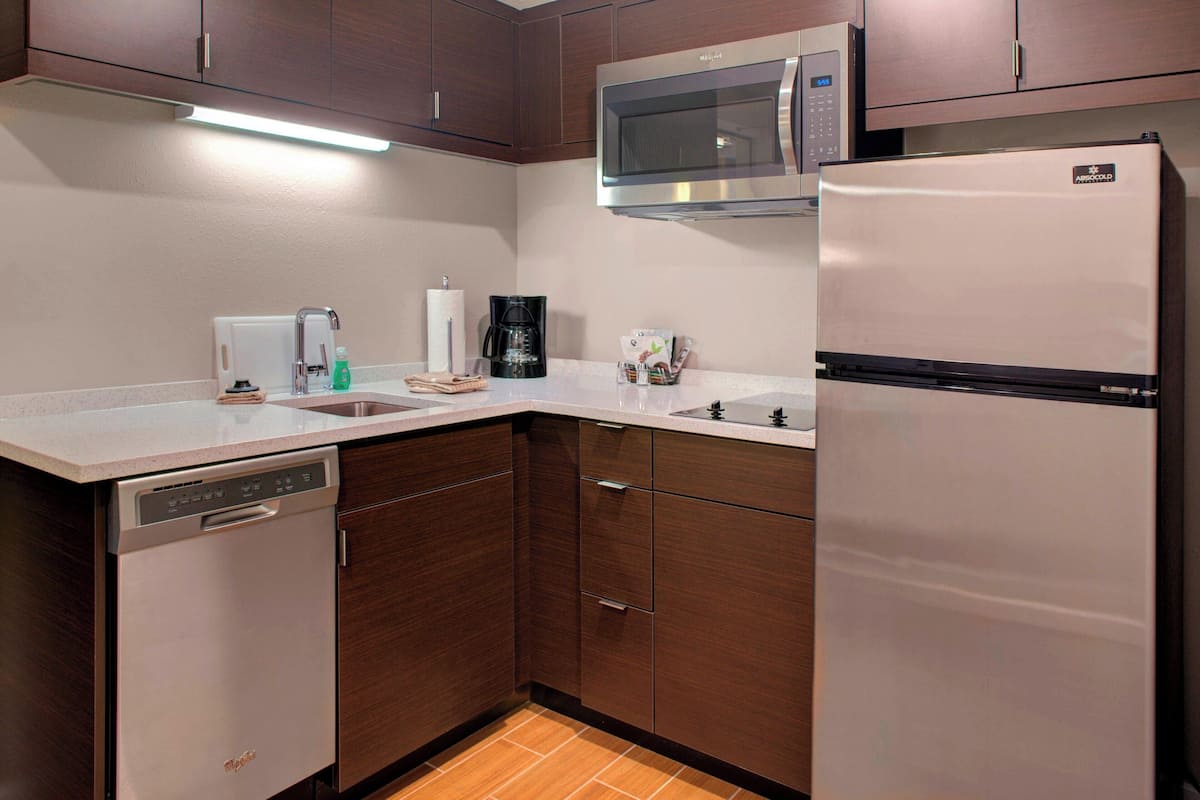 A modern kitchen with a dishwasher, microwave, and refrigerator.