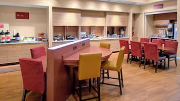 Een restaurant met een lange toonbank, rode stoelen en een houten vloer.