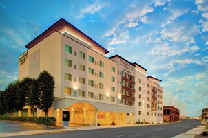 Un hotel de varios pisos con diseño moderno, que cuenta con una entrada destacada con área cubierta y un letrero visible que indica que es un TownePlace Suites Marriott.