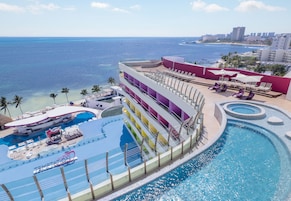 Un resort con piscina, sillas de descanso y vista al océano.