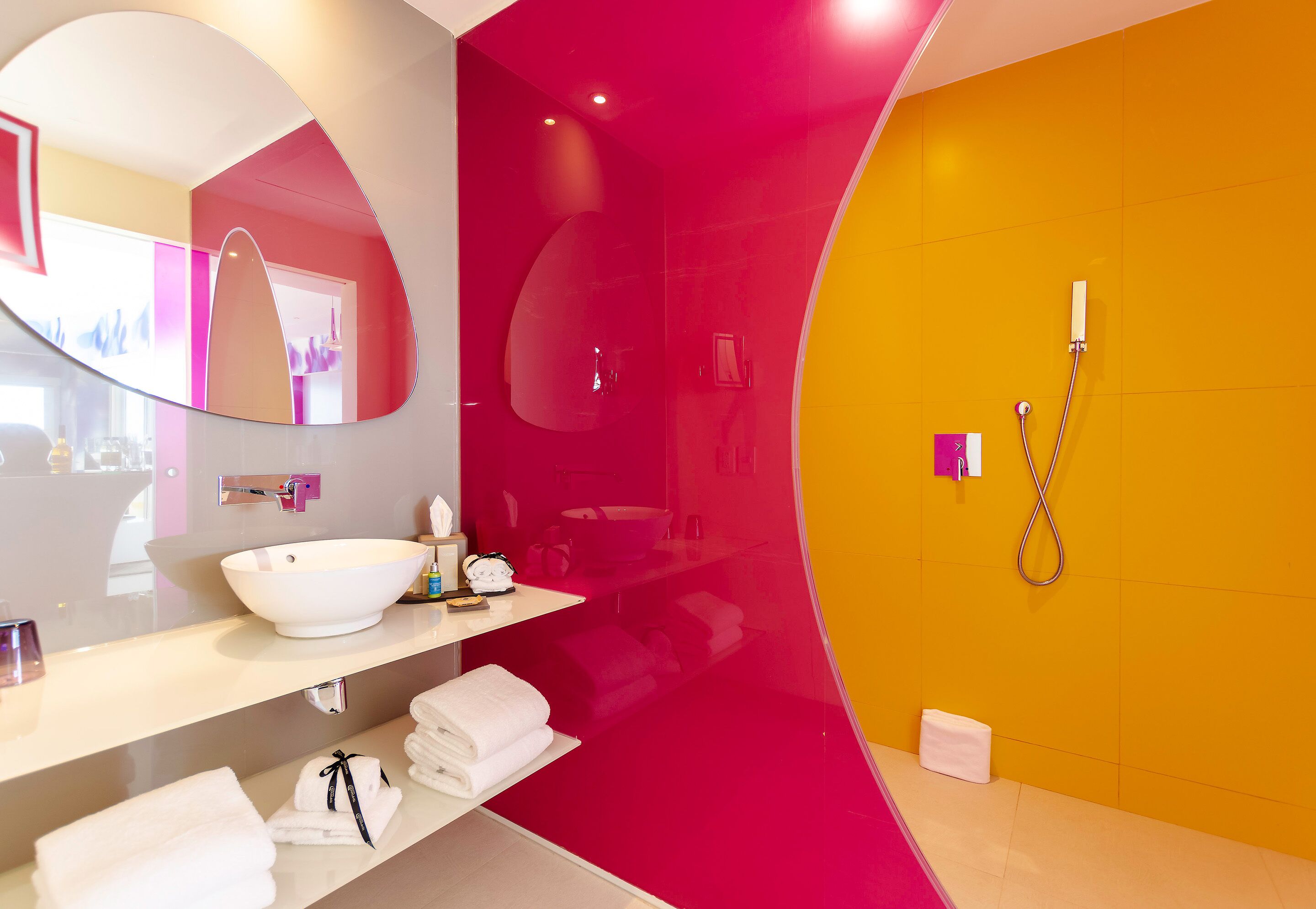 Un baño moderno con un espejo grande, un lavamanos blanco y una zona de ducha.