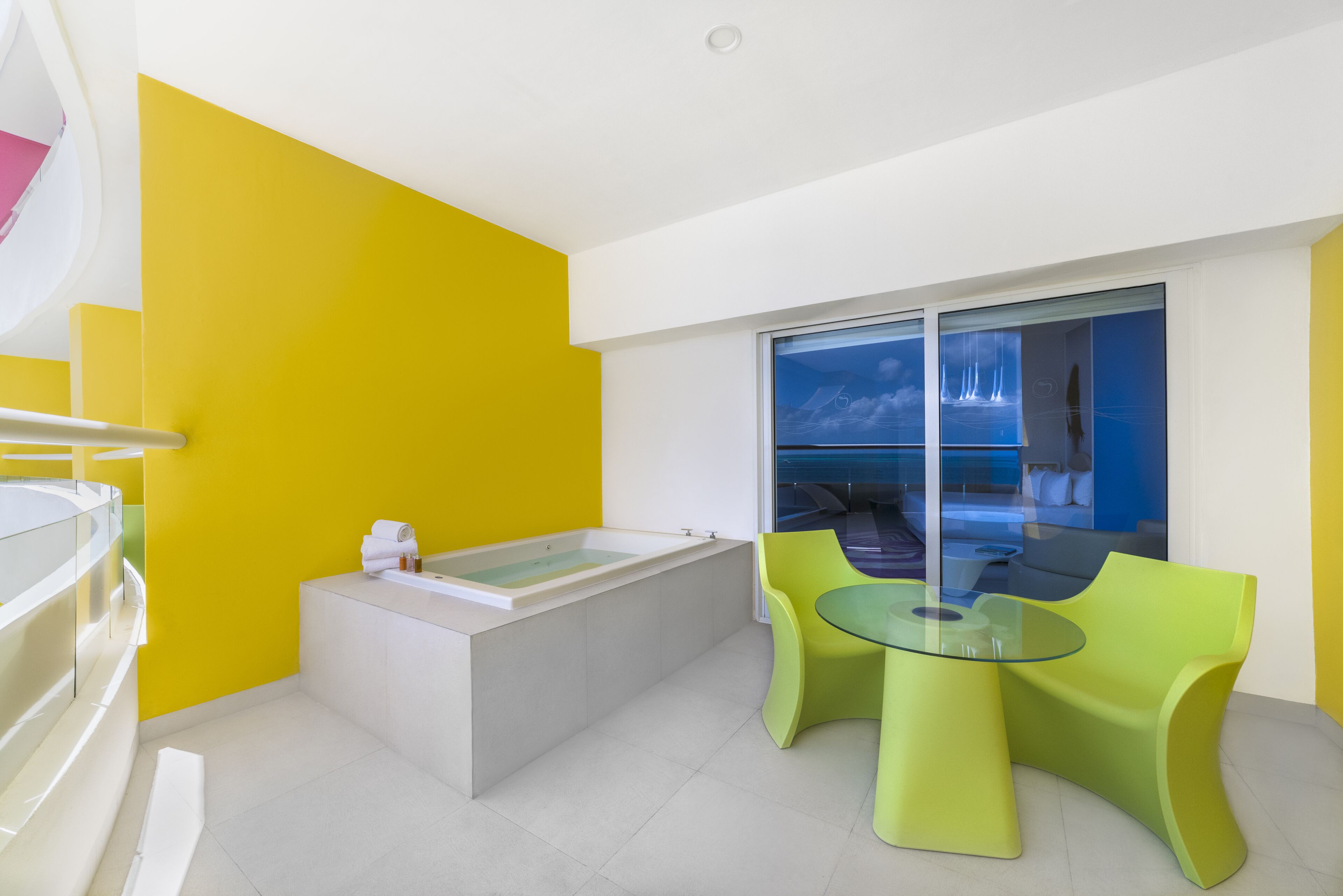 Un baño moderno con bañera, cabina de ducha de vidrio y pared de acento amarilla.
