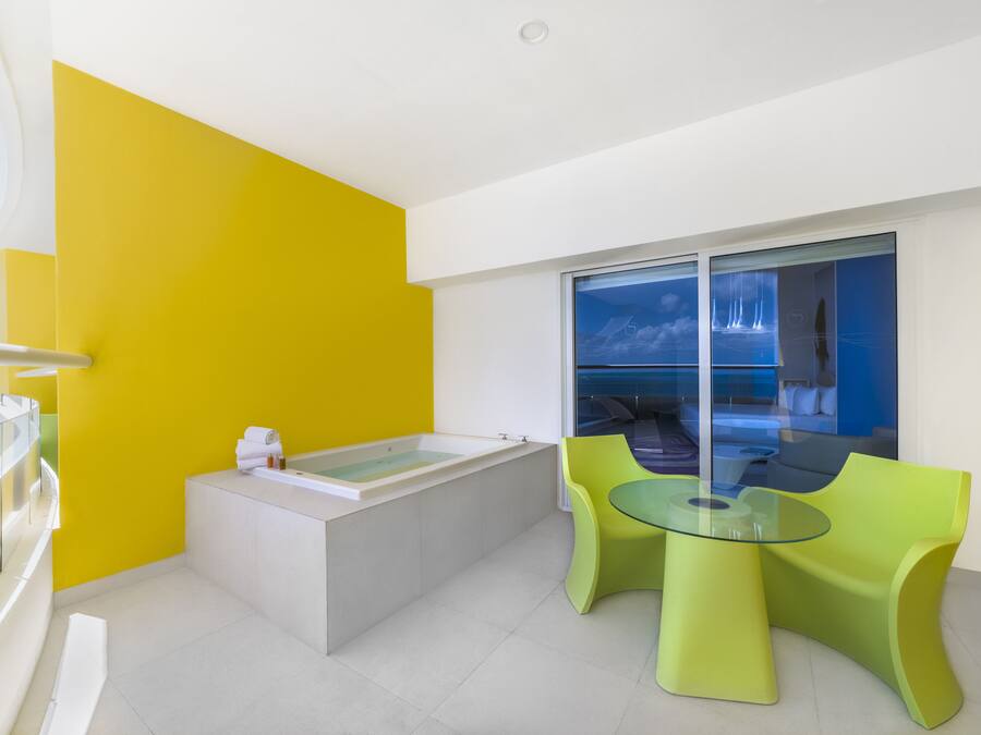Un baño moderno con bañera, cabina de ducha de vidrio y pared de acento amarilla.