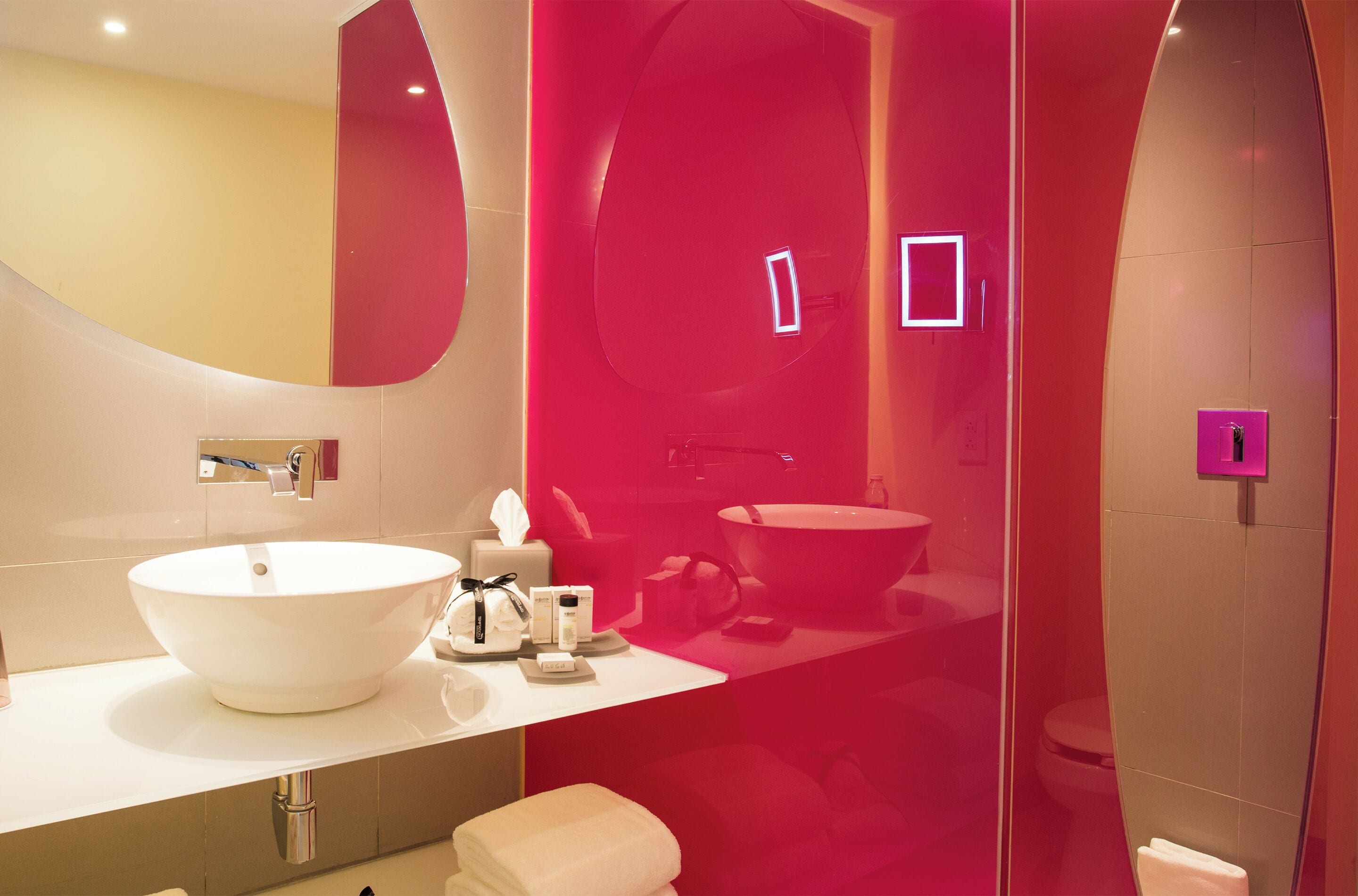 Un baño moderno con un lavamanos blanco grande, un espejo y un inodoro.