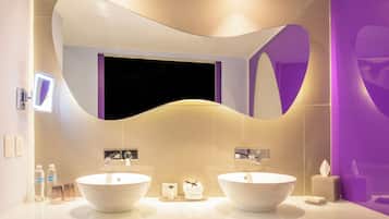 A modern bathroom with two sinks, a large mirror, and a purple accent wall.