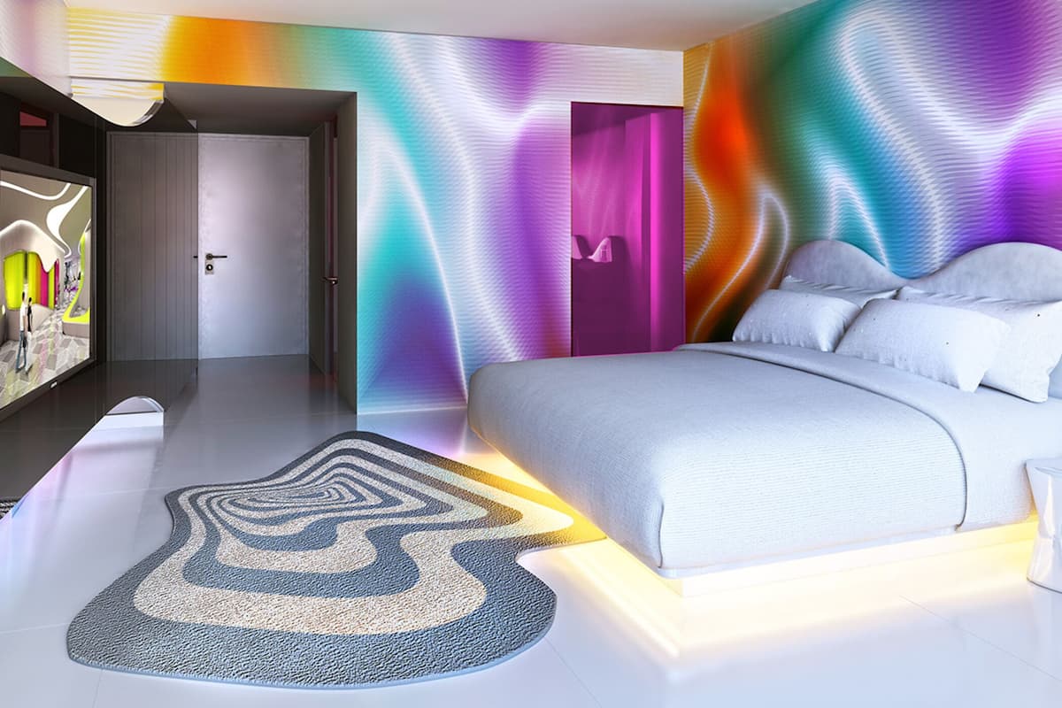 A modern bedroom with a bed, a door, and a wall with a wavy pattern.