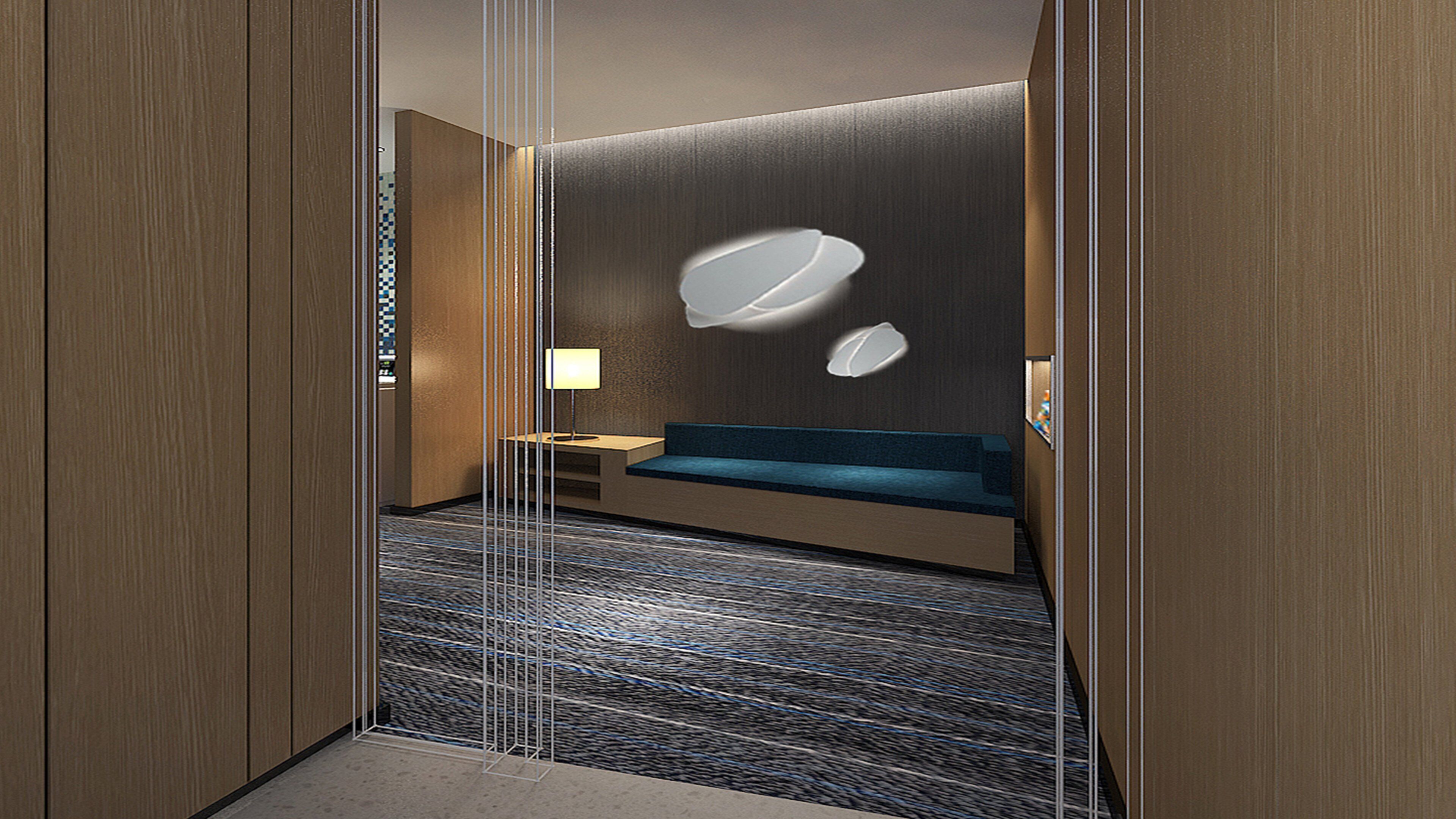 Une chambre d’hôtel équipée d’un lit, d’un bureau, d’une lampe et d’un luminaire fixé au mur.