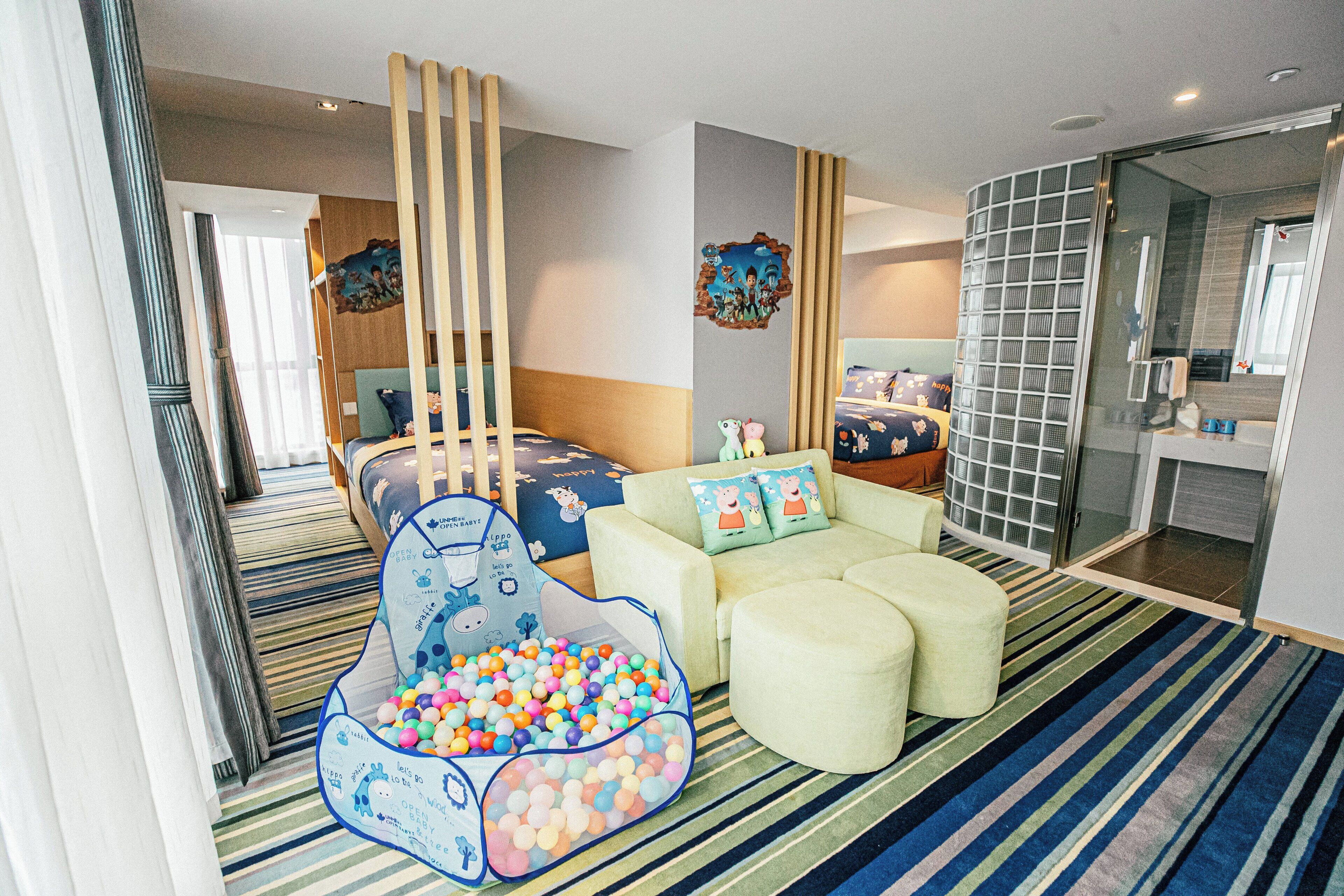 Zona de juegos para niños con piscina de pelotas, un sofá y una cama de diseño azul y blanco.
