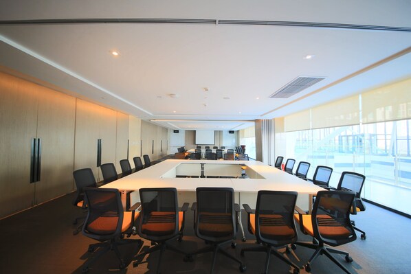 A conference room with a long table and chairs, large windows, and a modern interior design.