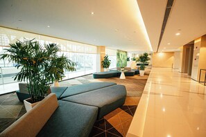 Un vestíbulo moderno con zonas de estar, ventanas amplias y plantas de interior.