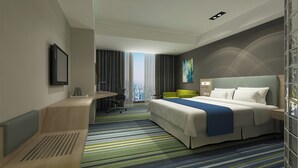 Moderni hotellihuone, jossa on suuri sänky, työpöytä ja näkymä kaupunkiin.