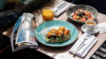 A table with a meal, a glass of orange juice, a cup of coffee, and a magazine.