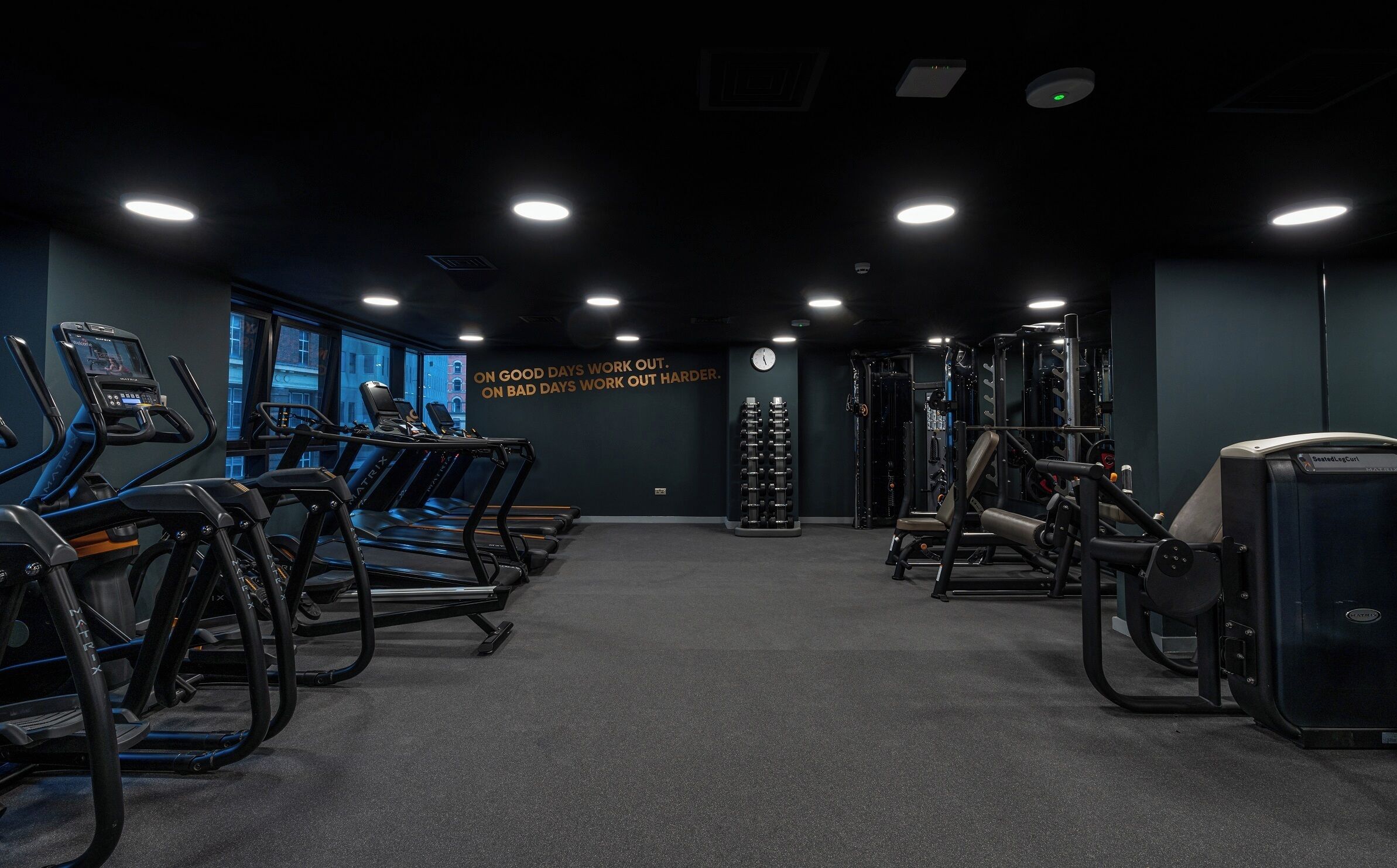 A gym with treadmills, weight machines, and a motivational quote on the wall.